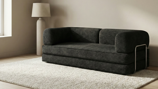 Black sofa in a minimalistic room with a lamp and rug.